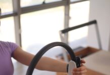 필라테스의 과학적 근거와 신체에 미치는 영향 a woman sitting on the floor holding a steering wheel