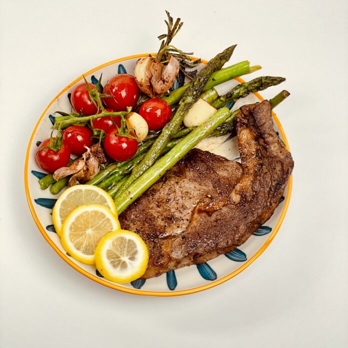 Photo by 哲 李 a plate of steak, asparagus, tomatoes, and asparagus