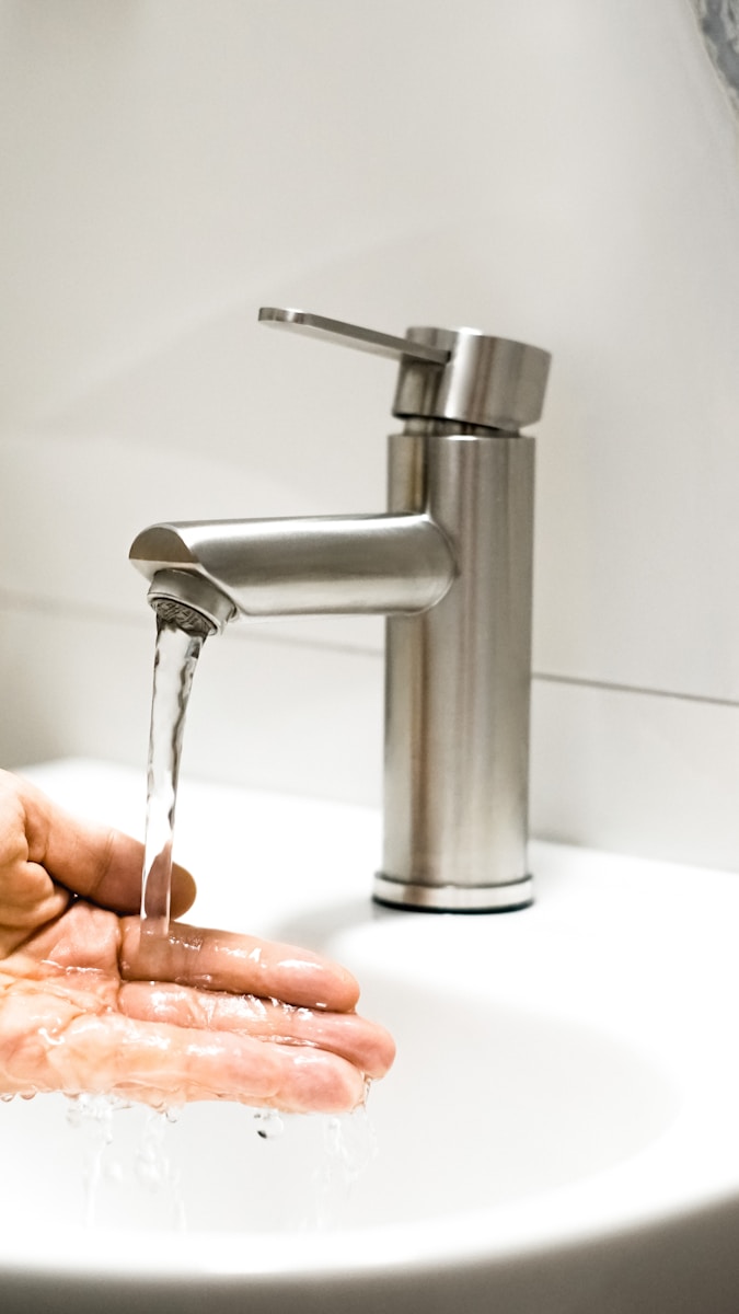 Photo by Cristi Ursea a person washing their hands under a faucet