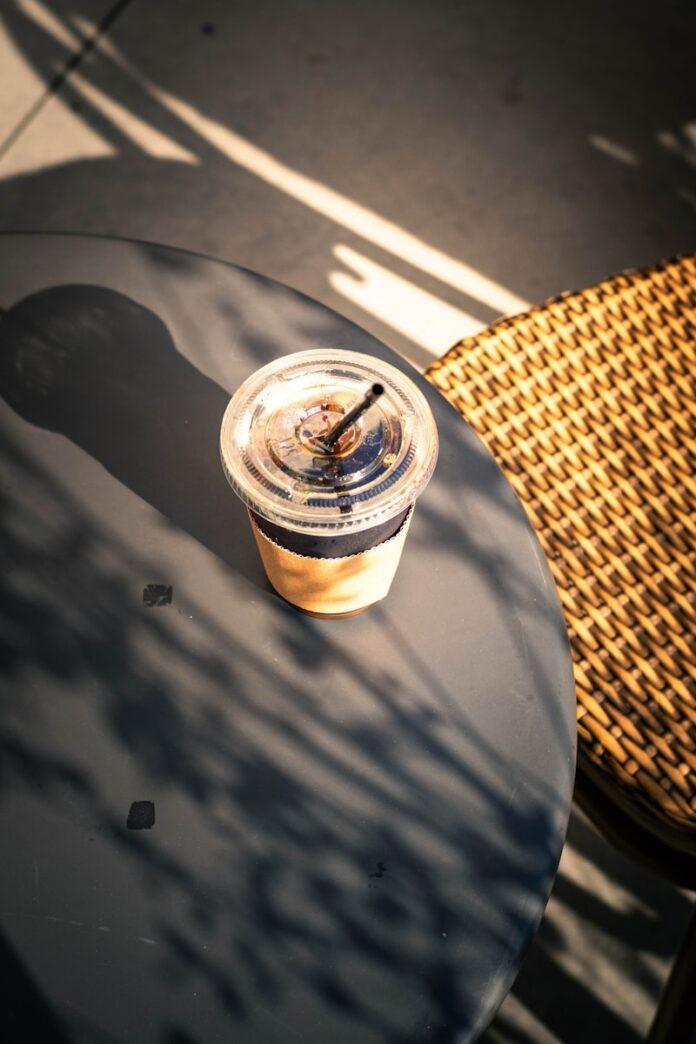 Photo by Madeline Liu Iced coffee on a table with dappled sunlight